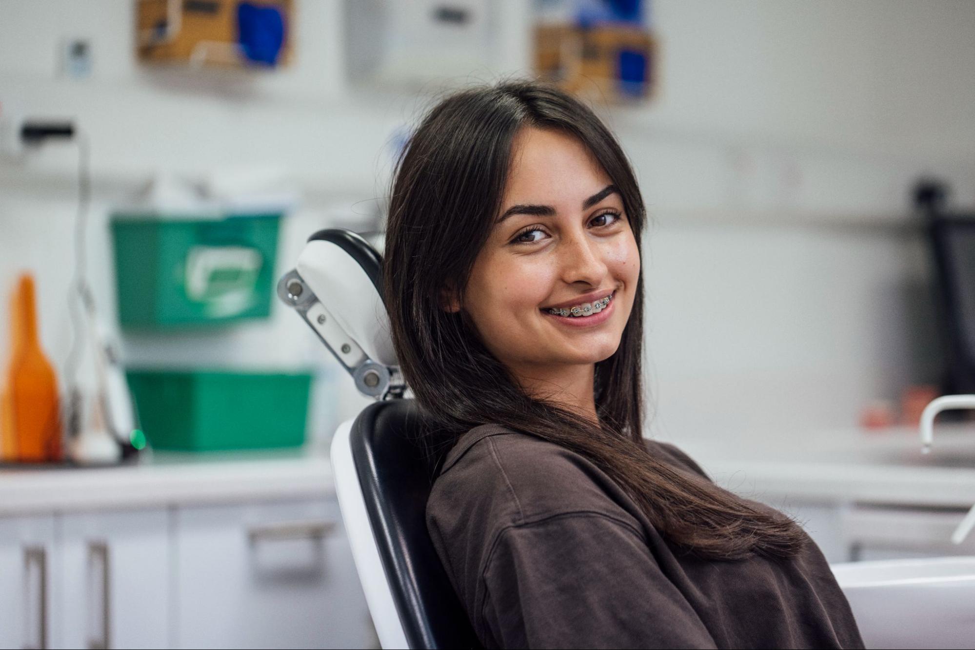 Smiling young girl with braces in orthodontic chair, representing Cherry Hills orthodontics and clear aligners options at 303 Smiles.